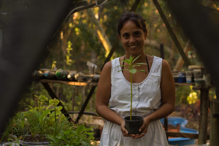 Foto da Maira Sagnori segurando uma muda de planta, parte da série Mulheres Inkiri: voz em mãos